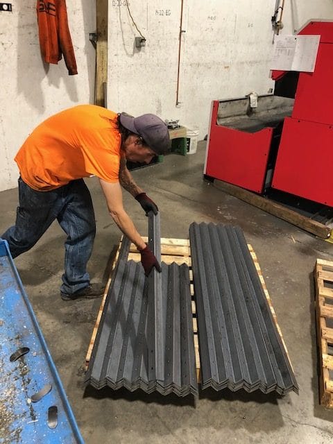 SMF employee setting down a corner brace on a pile of other corner braces